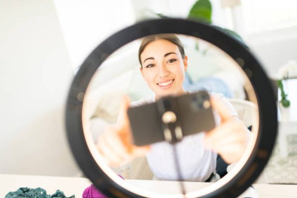 Young Woman Influencer setting up smart phone in ring light for crochet vlog